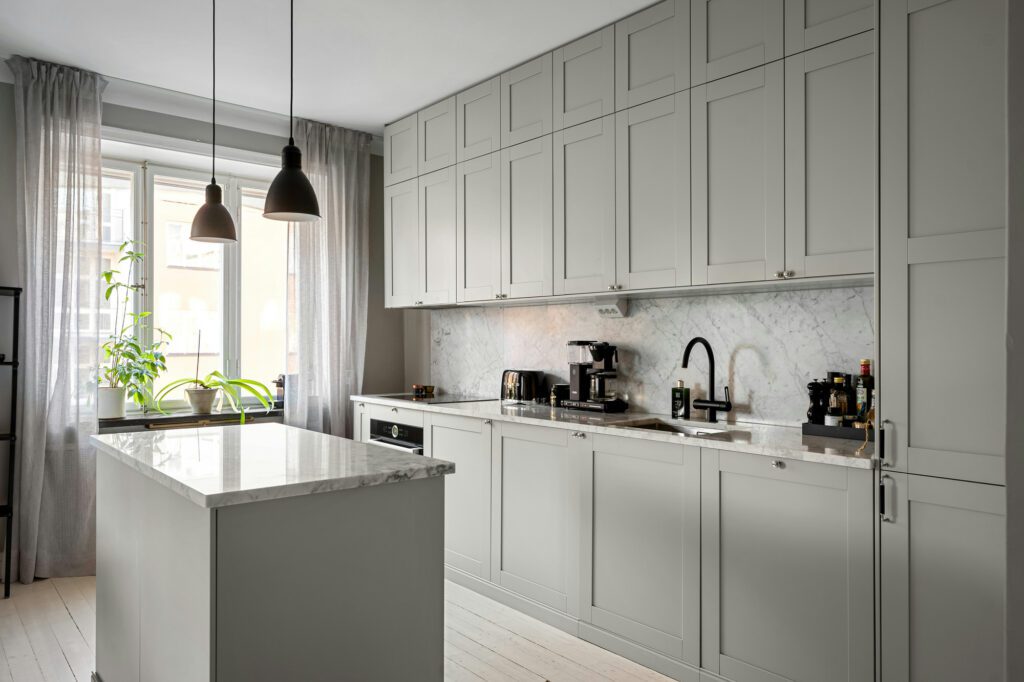Cuisine moderne grise avec îlot central et plan de travail en marbre. Cuisiniste Normandie.