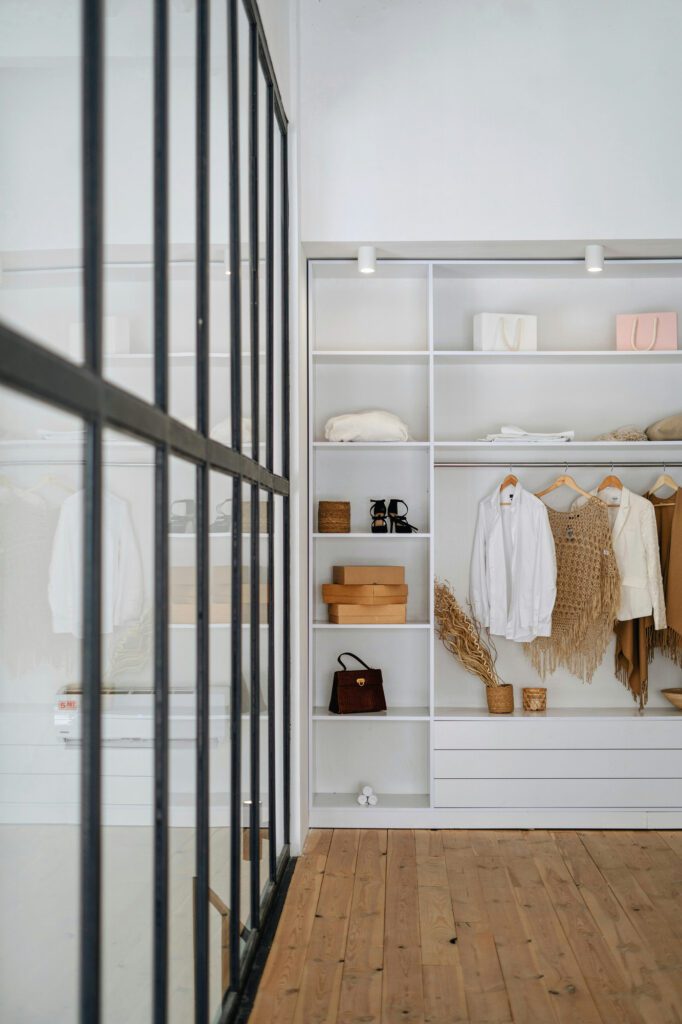Dressing sur mesure blanc avec verrière atelier noire, étagères ouvertes, penderie et tiroirs — aménagement lumineux et organisé par un cuisiniste.