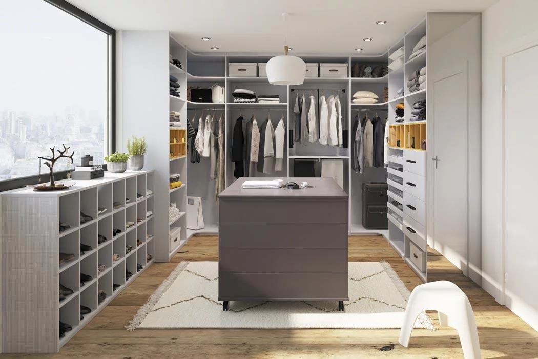 Dressing sur mesure avec îlot central à tiroirs, penderies murales, étagères et rangement chaussures — aménagement complet par un cuisiniste.